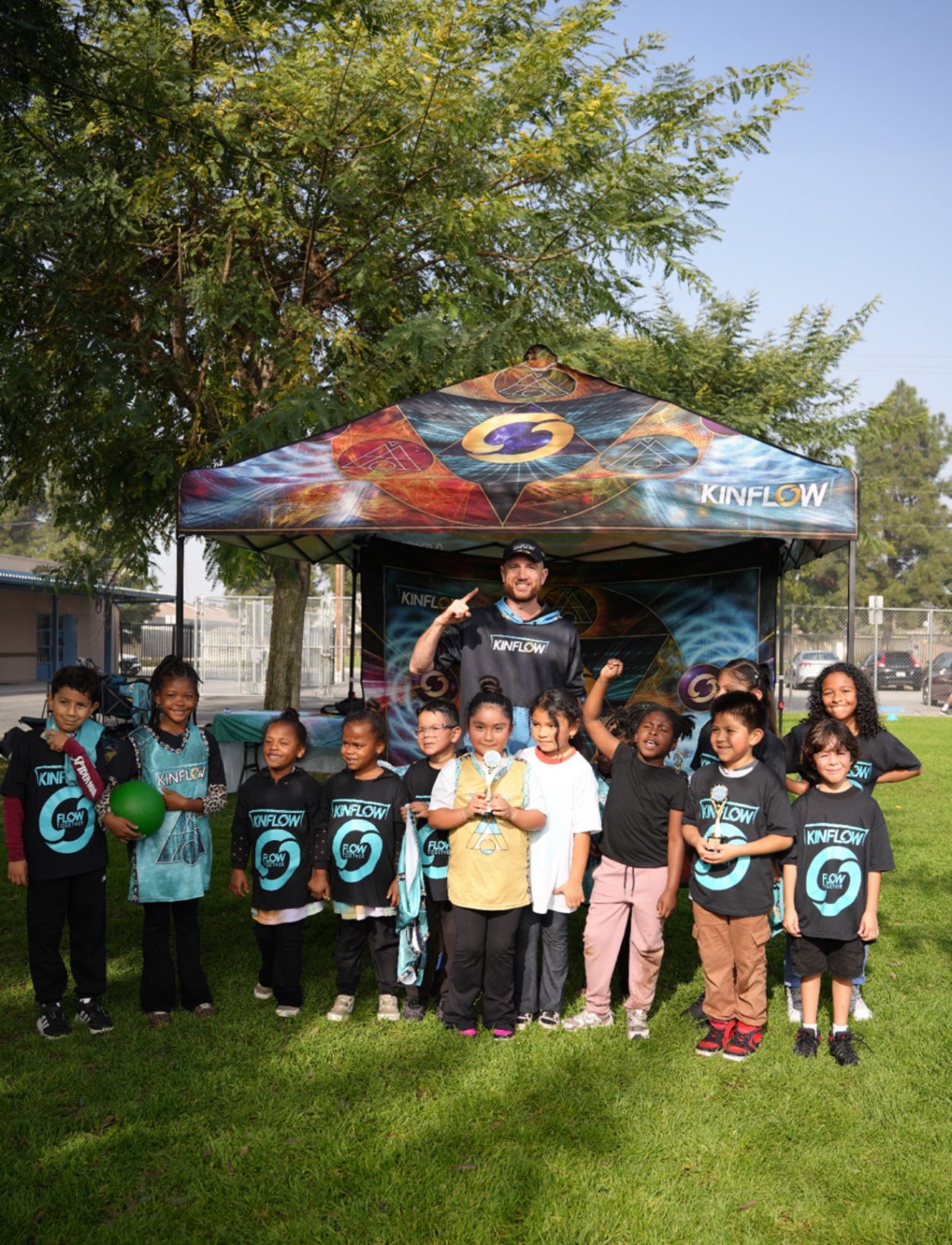 Young KinFlow players holding trophies with their coach in front of the KinFlow tent